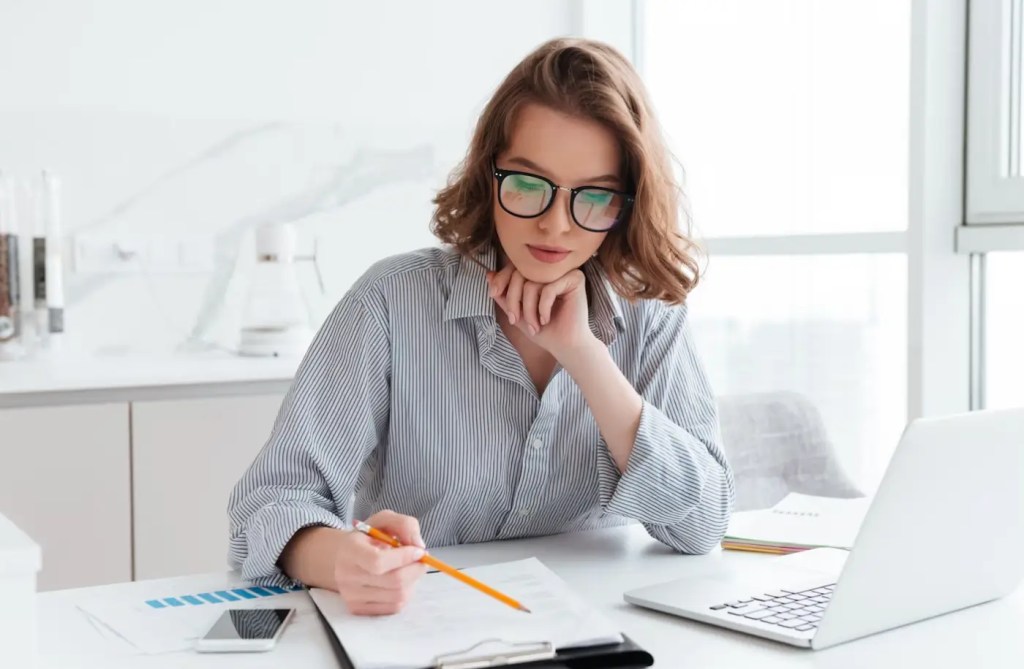 imagem de mulher de óculos estudando uma planilha para abordar cursos de finanças pessoais gratuitos para micro empreendedores