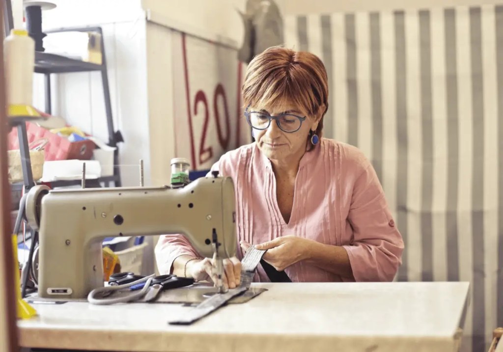 imagem de mulher trabalhado em máquina de costura para falar sobre aposentadoria de MEI